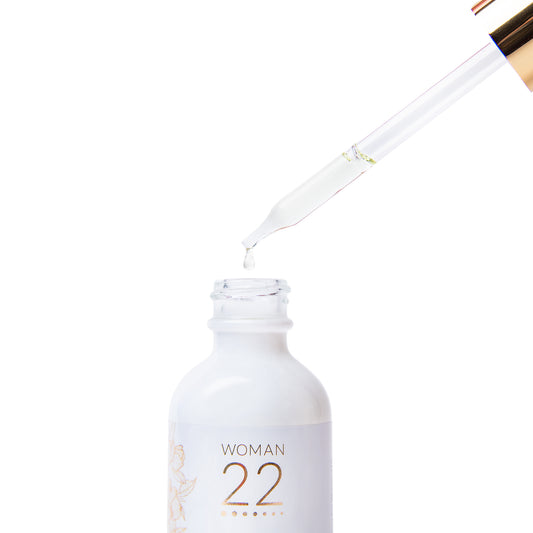 Woman 22 Golden Rainforest Serum dropper showing the lightweight golden serum – crafted with rainforest botanicals for daily self-care and soothing comfort